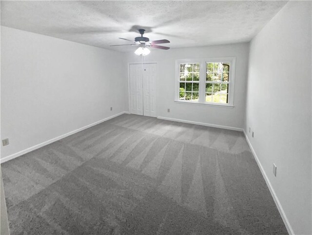 carpeted spare room featuring a textured ceiling, baseboards, and a ceiling fan