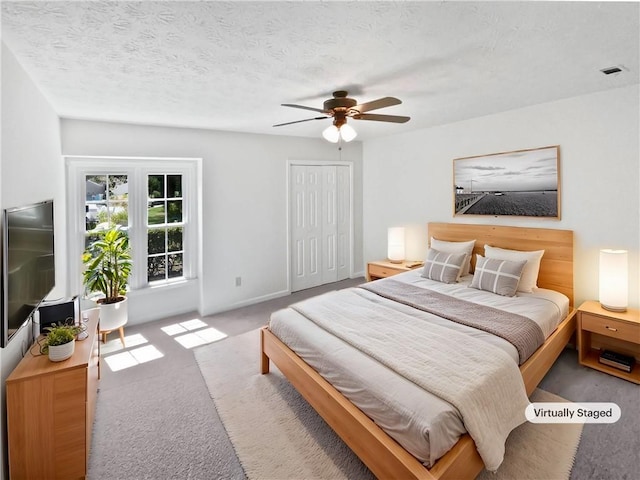 carpeted bedroom with visible vents, ceiling fan, a closet, and a textured ceiling