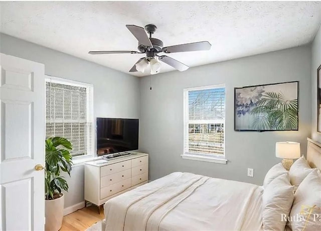 bedroom with a textured ceiling, light wood-style floors, and ceiling fan