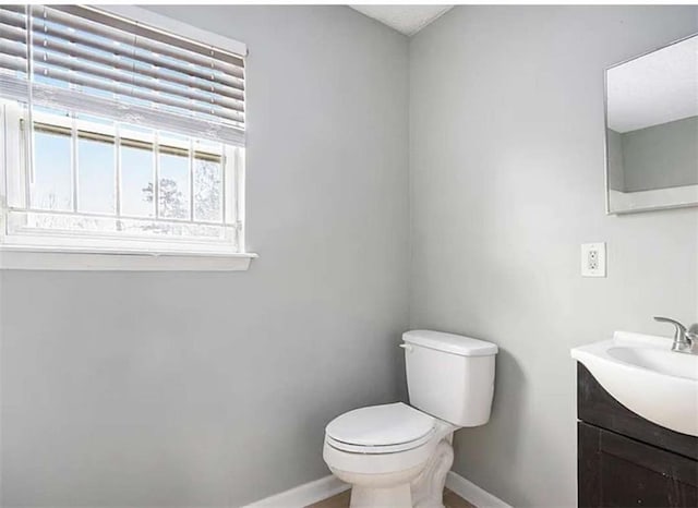 bathroom with vanity, toilet, and baseboards