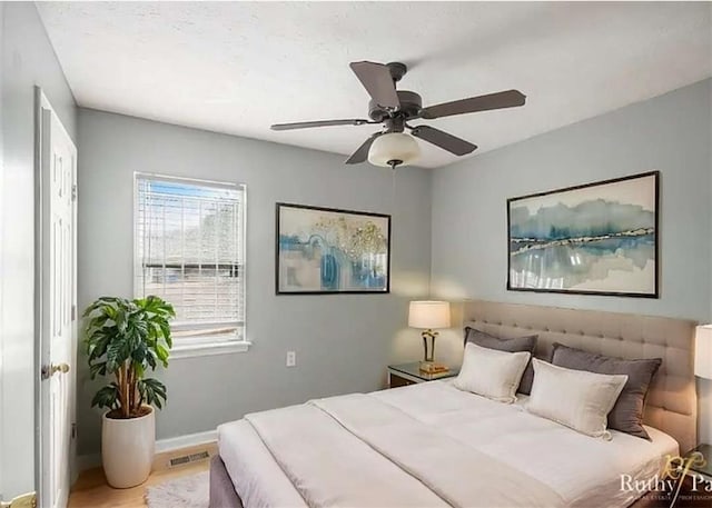 bedroom featuring visible vents, ceiling fan, baseboards, and wood finished floors