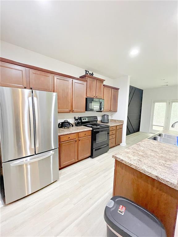 3130 Haynes Park Dr, Lithonia, GA 30038 - kitchen with black appliances, a sink, light countertops, light wood finished floors, and brown cabinets