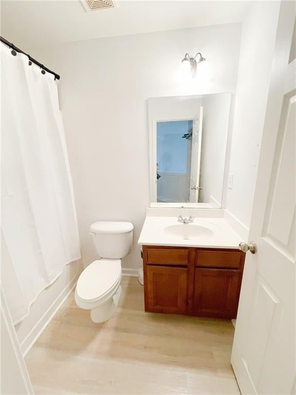3130 Haynes Park Dr, Lithonia, GA 30038 - bathroom featuring vanity, wood finished floors, toilet, and shower / bathtub combination with curtain