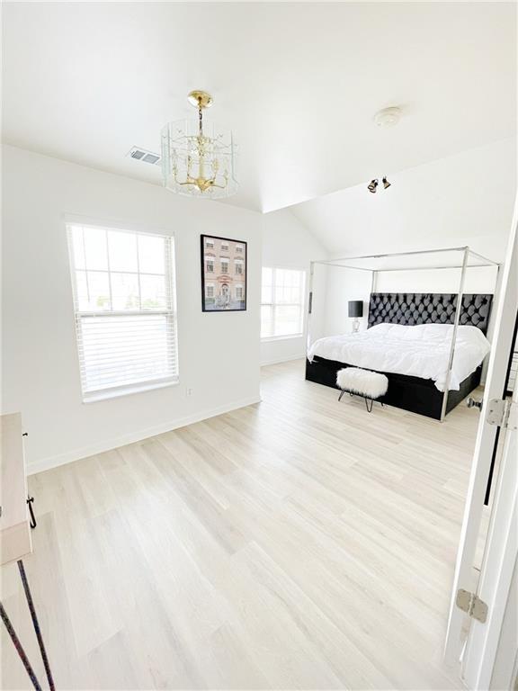 3130 Haynes Park Dr, Lithonia, GA 30038 - unfurnished bedroom featuring light wood-type flooring, a chandelier, vaulted ceiling, and baseboards