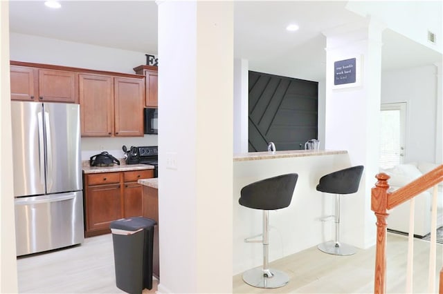 3130 Haynes Park Dr, Lithonia, GA 30038 - kitchen with black appliances, a breakfast bar area, light countertops, light wood-style flooring, and recessed lighting