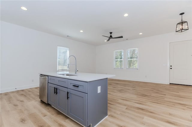 kitchen featuring recessed lighting, gray cabinets, stainless steel dishwasher, a sink, and light wood-type flooring