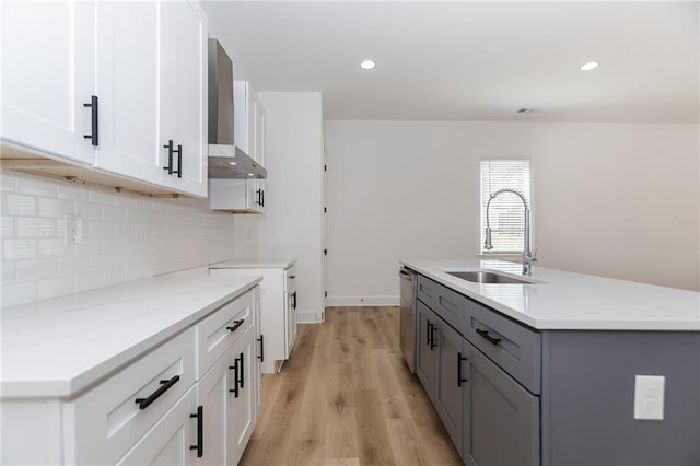 kitchen featuring a sink, decorative backsplash, light stone countertops, dishwasher, and wall chimney exhaust hood