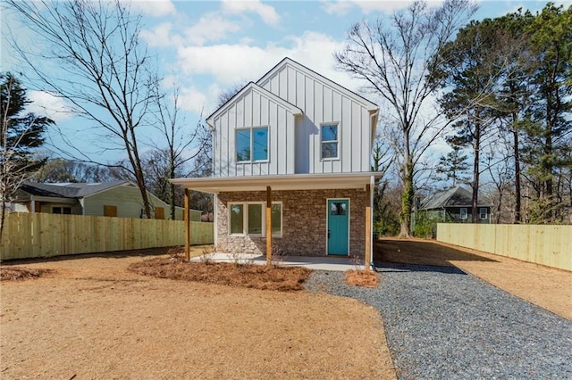 view of front of home featuring driveway, fence, board and batten siding, and brick siding