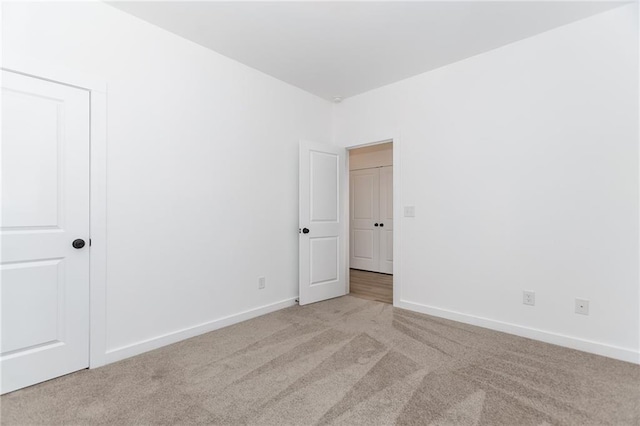 unfurnished room featuring light carpet and baseboards