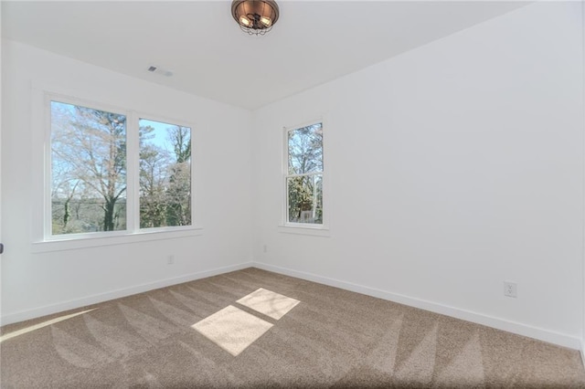 empty room featuring carpet, visible vents, and baseboards