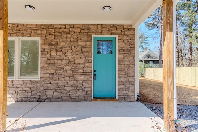 entrance to property with stone siding and fence