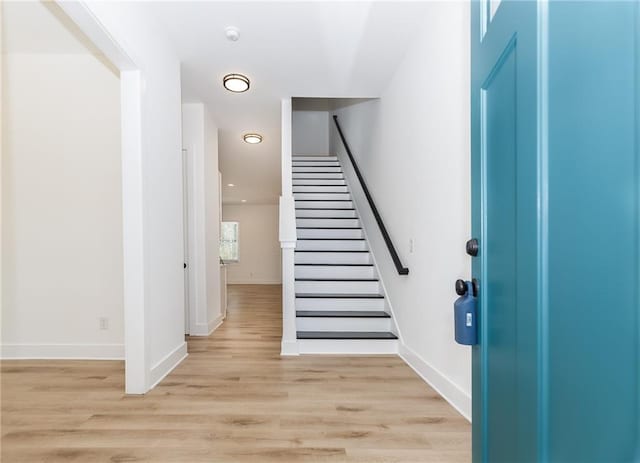 entryway with light wood finished floors, stairway, and baseboards