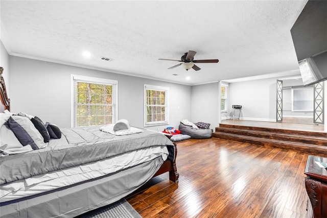 bedroom featuring ceiling fan, crown molding, dark wood-type flooring, and a textured ceiling