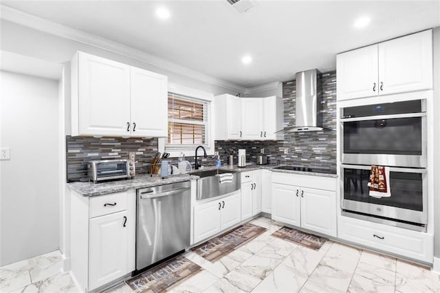 kitchen with appliances with stainless steel finishes, tasteful backsplash, light stone counters, wall chimney range hood, and white cabinets