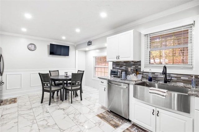 kitchen with light stone countertops, dishwasher, sink, white cabinets, and ornamental molding