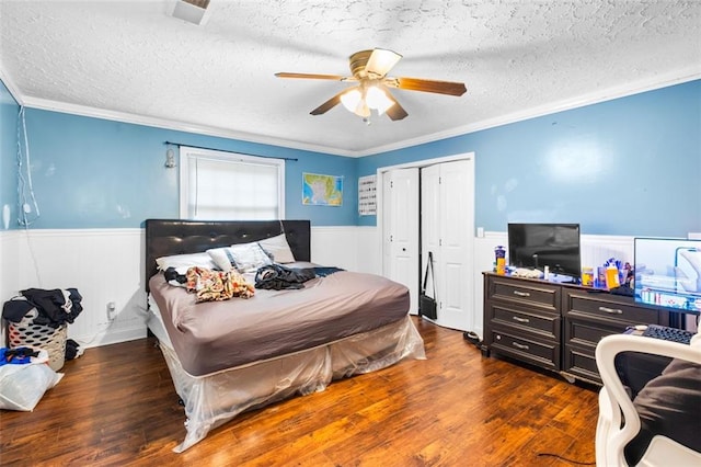 bedroom with ornamental molding, a textured ceiling, ceiling fan, and dark wood-type flooring