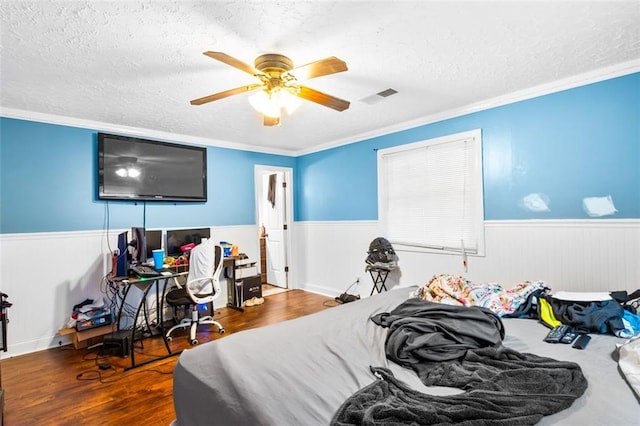 bedroom featuring ceiling fan, ornamental molding, a textured ceiling, and hardwood / wood-style flooring