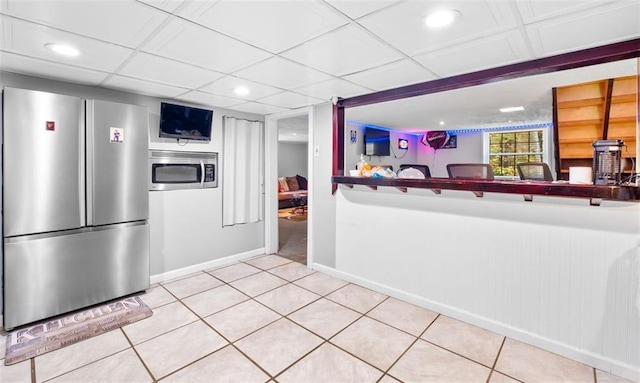 kitchen with a paneled ceiling, stainless steel appliances, and tile patterned floors