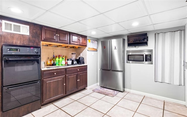 kitchen featuring light tile patterned floors, a paneled ceiling, and stainless steel appliances