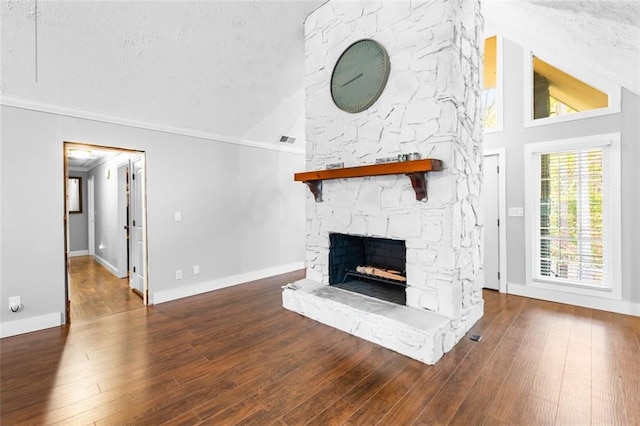 unfurnished living room featuring a stone fireplace, high vaulted ceiling, crown molding, a textured ceiling, and hardwood / wood-style flooring