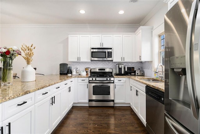 kitchen with tasteful backsplash, appliances with stainless steel finishes, sink, and white cabinets