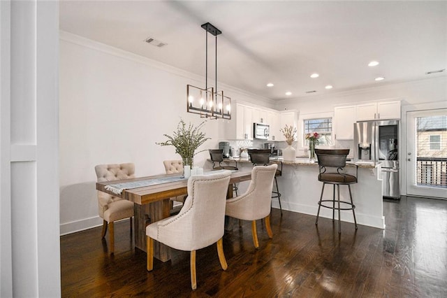 dining room with ornamental molding, a notable chandelier, and dark hardwood / wood-style flooring