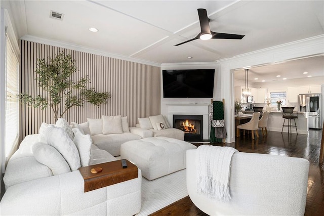 living room featuring dark wood-type flooring, ornamental molding, and ceiling fan