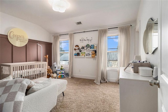 carpeted bedroom with a crib and vaulted ceiling