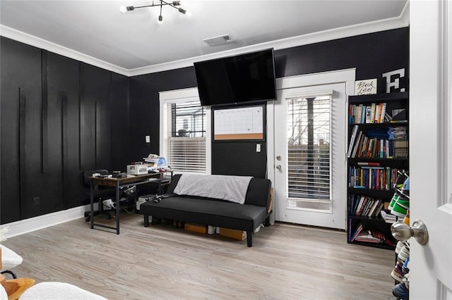 sitting room with ornamental molding and light wood-type flooring