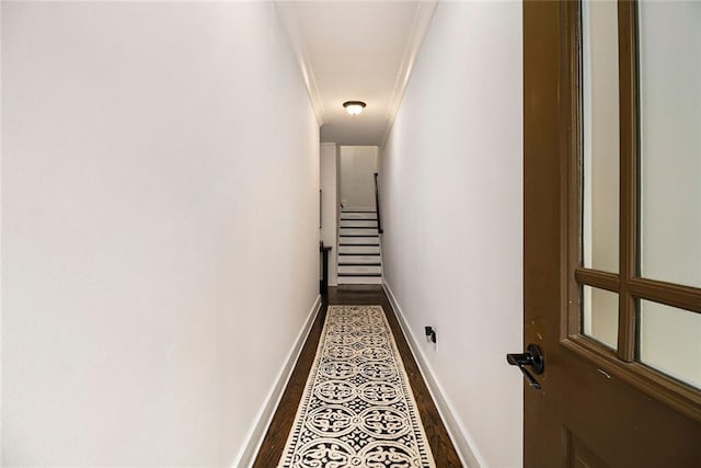 hallway with dark wood-type flooring and ornamental molding