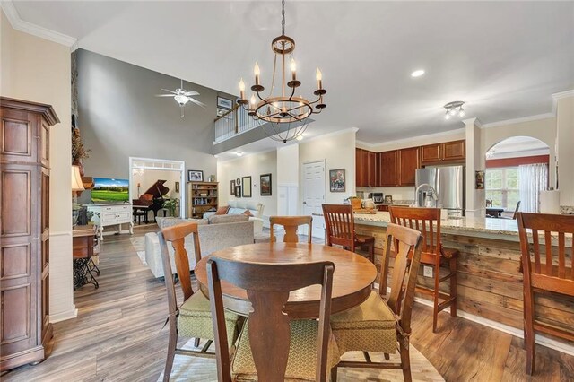 dining room with light wood-style flooring, a chandelier, ornamental molding, and a wainscoted wall
