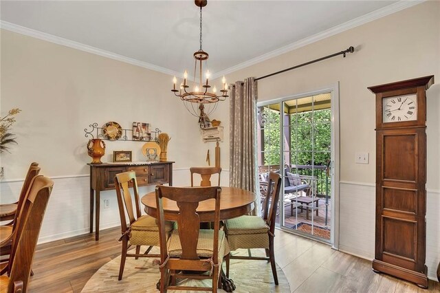 dining room featuring a chandelier, light wood finished floors, ornamental molding, and wainscoting