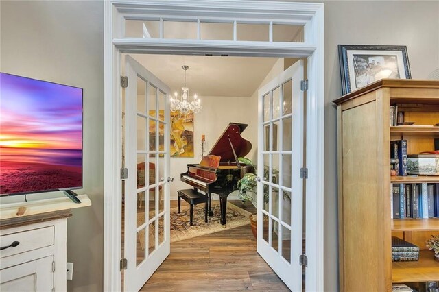 sitting room with french doors, wood finished floors, a chandelier, and baseboards