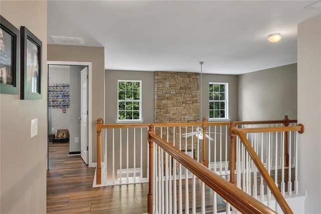 hall featuring an upstairs landing, wood finished floors, and baseboards