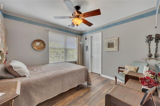 bedroom with wood finished floors, baseboards, and a ceiling fan