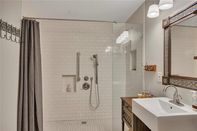 bathroom with a tile shower and vanity