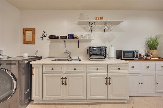 laundry area featuring washer / dryer, cabinet space, and light tile patterned floors
