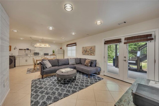 living room featuring light tile patterned flooring, plenty of natural light, washer / dryer, recessed lighting, and a chandelier