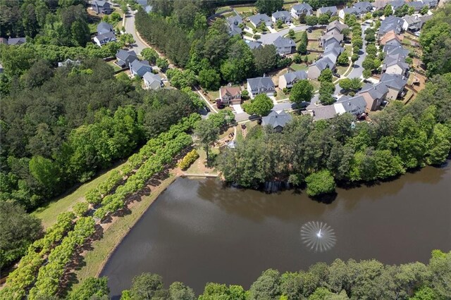 aerial overview of property's location with a large body of water, nearby suburban area, and a tree filled landscape