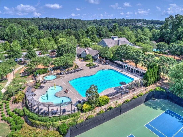drone / aerial view of a heavily wooded area and a pool