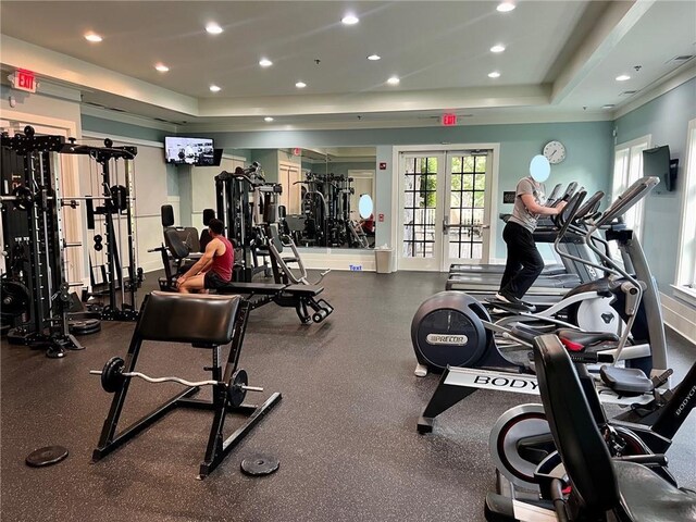 exercise room with a raised ceiling, recessed lighting, and french doors