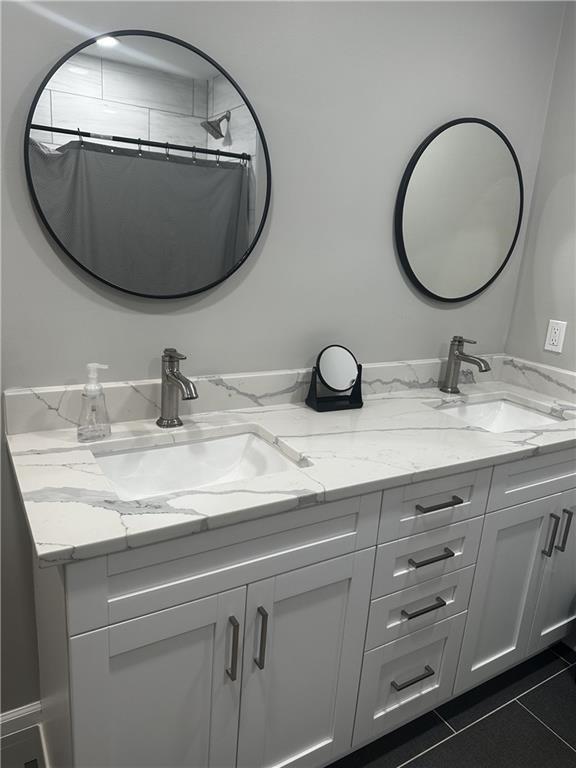 bathroom with curtained shower, tile patterned flooring, a sink, and double vanity