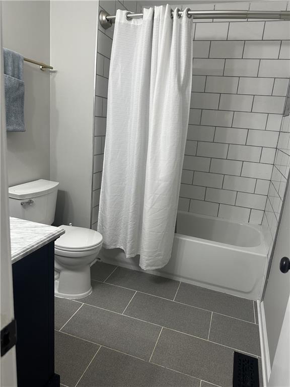 full bath featuring toilet, tile patterned flooring, shower / bath combination with curtain, and vanity