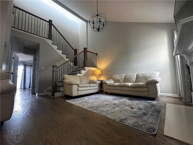 living room with a towering ceiling, an inviting chandelier, baseboards, and stairway