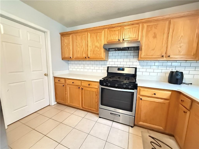 2658 Deann Dr, Ellenwood, GA 30294 - kitchen featuring stainless steel gas range, under cabinet range hood, light countertops, and backsplash