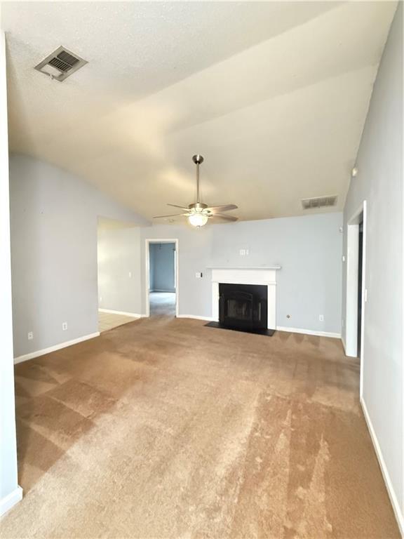 2658 Deann Dr, Ellenwood, GA 30294 - unfurnished living room featuring ceiling fan, carpet flooring, a fireplace with flush hearth, and lofted ceiling
