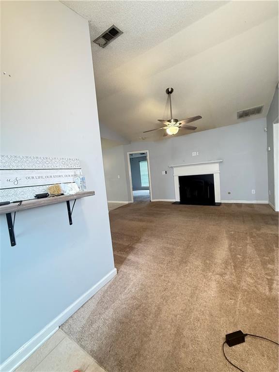 2658 Deann Dr, Ellenwood, GA 30294 - unfurnished living room featuring a ceiling fan, carpet flooring, and a fireplace