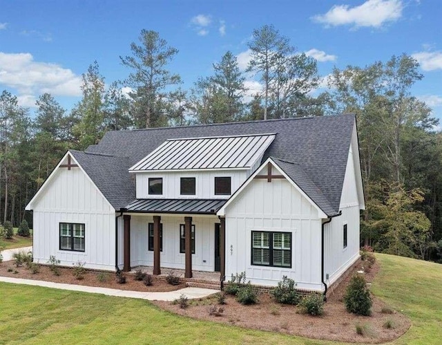 modern farmhouse featuring covered porch, a standing seam roof, a front yard, and board and batten siding