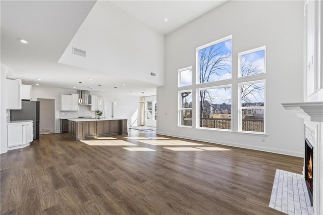 unfurnished living room featuring dark wood-type flooring and a high ceiling