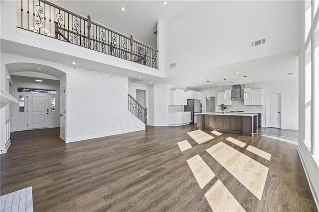 unfurnished living room with dark hardwood / wood-style flooring and a towering ceiling